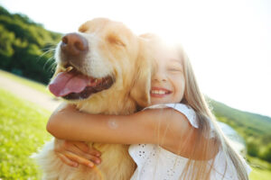 young-girl-hugging-golden-retriever-outdoors-on-a-sunny-day